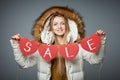 Girl in winter coat with hood on holding four hearts garland