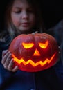 Girl in witch costume, hat with jack-o-lantern.Hand made from big pumpkin. Candle lights in eyes,nose,mouth. Celebratiion of Royalty Free Stock Photo