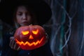 Girl in witch costume, hat with jack-o-lantern.Hand made from big pumpkin. Candle lights in eyes,nose,mouth Royalty Free Stock Photo