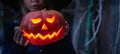 Girl in witch costume, hat with jack-o-lantern.Hand made from big pumpkin. Candle lights in eyes,nose,mouth. Celebratiion of Royalty Free Stock Photo