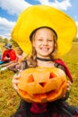 Girl in witch costume holds pumpkin with hands Royalty Free Stock Photo