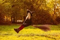 A girl in a witch costume sits on a floating broom Royalty Free Stock Photo