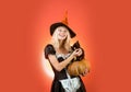 Girl witch plays with black kitten Halloween Witch in black hat. Black cat sits on a pumkin. Girl witch plays with black Royalty Free Stock Photo