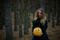 Girl witch witch pumpkin on halloween in a dark pine forest