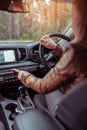 Girl woman in car interior leather jacket autumn and spring, in forest park, presses emergency stop button, switches on Royalty Free Stock Photo