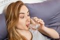 Girl woman drink water in bed at home, healthcare concept, hangover Royalty Free Stock Photo