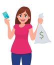 Girl/woman/female holding or showing credit, debit or ATM bank card & money, cash/currency note bag with dollar sign. Modern.