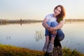 Girl or woman sitting on the shore or beach of the lake in the evening at sunset. Single trip or vacation