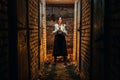 A girl, a woman in traditional Ukrainian clothing stands in a dark basement with a candle in her hands. The concept of a tragedy