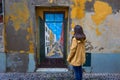 Girl Woman Traveler looking at a painted door on a traditional street in Funchal, Madeira, Portugal