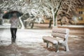 Girl or woman walking on the strees with umbrella in snowstorm, bench with snow in the city, night photography Royalty Free Stock Photo