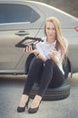 The girl wondered. Broken car on a background. Woman sit on a wheel. young woman repair a car. Natural background. Car accide Royalty Free Stock Photo