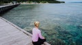 Girl on a wooden jetty near Yenbuba village leading to Mansuar island in Raja Ampat. Beautiful corals in transparent Royalty Free Stock Photo