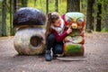 A girl at a wooden mushroom and worm sculptures in the autumn forest, Tervete, Latvia Royalty Free Stock Photo