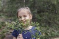 Girl in the woods with a sprig of blueberries looks at the camera Royalty Free Stock Photo