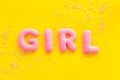 Girl word as decoration for baby shower on yellow background top view