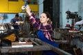 Girl worker is holding lift hook equipment in workshop.