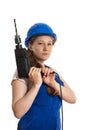 The girl in working clothes and a helmet holds a drill in hand.