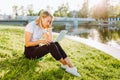 Girl working at the computer sittingon the grass in a protective medical mask on her face. Freelance, quarantine concept