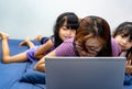 A girl working from home on her bed with laptop and headset being bothered by kids. Mommy working from home during stay home Royalty Free Stock Photo