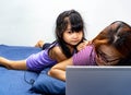 A girl working from home on her bed with laptop and headset being bothered by kids. Mommy working from home during stay home Royalty Free Stock Photo