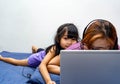 A girl working from home on her bed with laptop and headset being bothered by kids. Mommy working from home during stay home Royalty Free Stock Photo