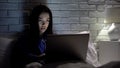 Girl working on laptop in bedtime, nervous about bugged software, slow internet