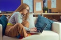 Girl works at home, sits on a sofa with a computer. Home schooling, online school. A girl looks at a computer, makes purchases Royalty Free Stock Photo