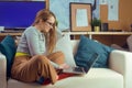 Girl works at home, sits on a sofa with a computer. Home schooling, online school. A girl looks at a computer, makes purchases Royalty Free Stock Photo