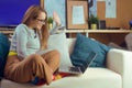 Girl works at home, sits on a sofa with a computer. Home schooling, online school. A girl looks at a computer, makes purchases Royalty Free Stock Photo