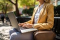 The girl works on a laptop while sitting on a park bench. Generative AI