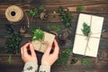 Girl wrapping christmas gift. Woman's hands holding decorated gift box on rustic wooden table. Christmas DIY packing. Royalty Free Stock Photo