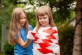 Girl wrapping her hyperactive sister in red white safety tape, sisters, siblings, friends playing. Children safety, kids