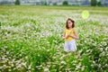 A girl with a wreath of daisies on her head and a net in her hands catches butterflies and has fun in a chamomile field in summer Royalty Free Stock Photo