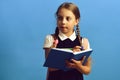 Girl writes in big blue notebook. Pupil in school uniform Royalty Free Stock Photo