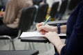 A girl writes a dictation or fills out documents in the audience, sitting on a school chair with a writing stand. Close-up