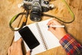 Girl writes in notebook with cell phone and camera Royalty Free Stock Photo