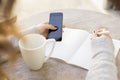 Girl writes in a notebook, with cell phone and cup of coffee Royalty Free Stock Photo