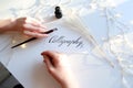 Girl writes pen fountain calligraphic letters, sitting at table Royalty Free Stock Photo