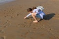 The girl writes the word `Love` and a symbol of heart on the sand at sunset. Footprints on the sea sand. Royalty Free Stock Photo