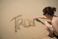 Girl writing the word travel in the sand