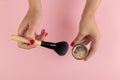 Girl& x27;s hands hold powder and makeup brush on a pink background, copy space Royalty Free Stock Photo