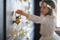 Girl of 8-9 years with delight admires gold Christmas-tree decorations. Royalty Free Stock Photo