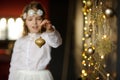 Girl of 8-9 years with delight admires gold Christmas-tree decorations. Royalty Free Stock Photo