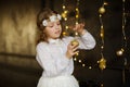 Girl of 8-9 years with delight admires gold Christmas-tree decorations. Royalty Free Stock Photo