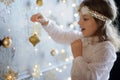 Girl of 8-9 years with delight admires gold Christmas-tree decorations. Royalty Free Stock Photo