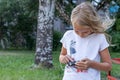 Girl, 6 years old, with a camera, little photographer, blonde, standing in the yard of the house, portrait of a child Royalty Free Stock Photo