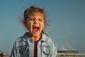 Portrait of emotional open-mouthed little girl on background of sky Royalty Free Stock Photo