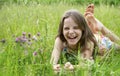 Girl 10 years old in a dress lying on the grass in a clearing and laughing