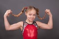 A girl athlete in a red sports swimsuit smiles and holds her hair in braids Royalty Free Stock Photo